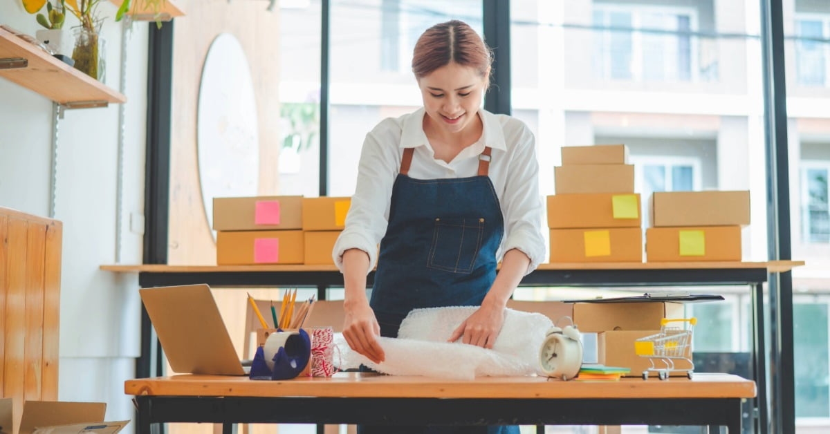 Mulher embalando pedidos de pequenos negócios que dão lucro
